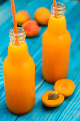 Glass of apricot and carrot juice on colourful turquoise blue painted wooden boards