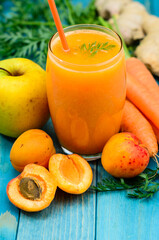 Glass of apricot and carrot juice on colourful turquoise blue painted wooden boards