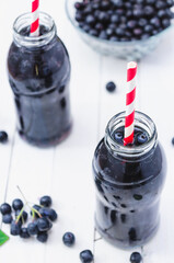 Cold delicious juice made of chokeberries on white wooden boards. Top View