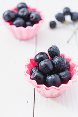 Chokeberry fruit in pink cup cake on a light wooden boards.