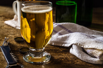 Glass of light beer on a dark brown table with snacks