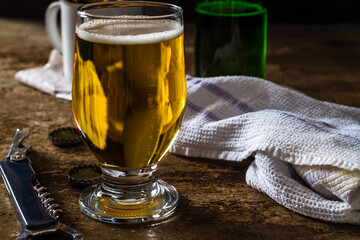 Glass of light beer on a dark brown table with snacks