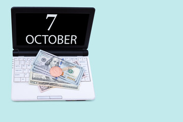 Laptop with the date of 7 october and cryptocurrency Bitcoin, dollars on a blue background. Buy or sell cryptocurrency. Stock market concept.