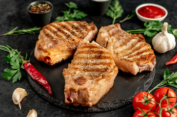 grilled pork steaks with spices on a stone background