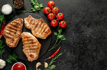 grilled pork steaks with spices on a stone background with copy space for your text.	
