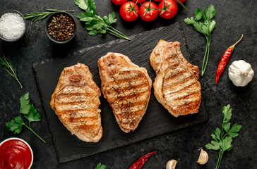 grilled pork steaks with spices on a stone background