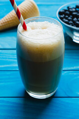  Glass of ice Coffee with cone and bowl of chokeberries on colourful turquoise blue painted wooden boards