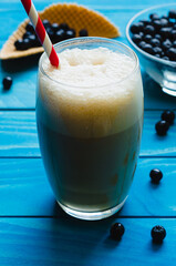 Glass of ice Coffee with cone and chokeberries on colourful turquoise blue painted wooden boards