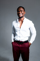 Cheerful african american man in a shirt in a tie and in trousers with hands in pockets smiling and looking at the camera