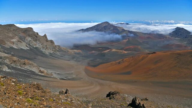 Haleakala Summit - A panoramic view of the colorful volcanic crater at summit of Haleakala, surrounded by sea of clouds and blue sky. Maui, Hawaii, USA.