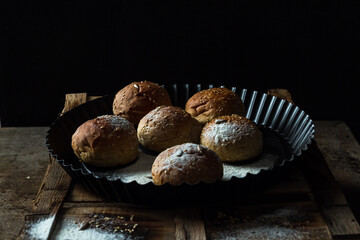 Whole wheat kaiser rolls with sesame seeds on retro crate in black pan