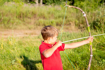 a boy in a red shirt shoots a homemade bow