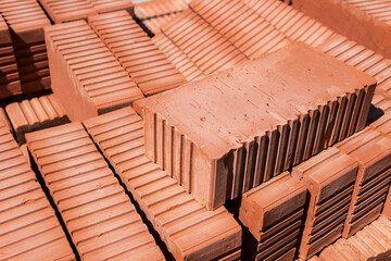 Obraz na płótnie Canvas Close-up of a brick lying on top of a stack of red bricks.