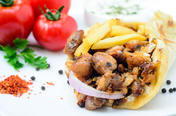 Plate of traditional Greek pita gyros with meat, fried potatoes, tomato and onion