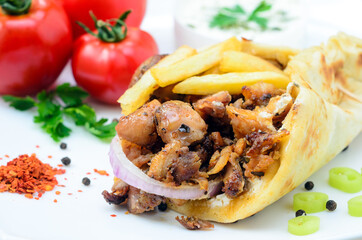 Plate of traditional Greek pita gyros with meat, fried potatoes, tomato and onion
