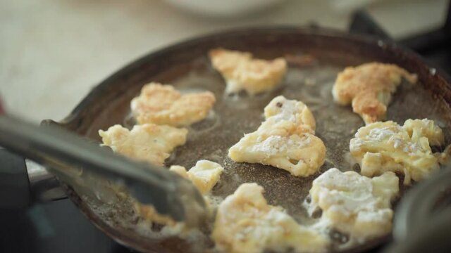 person roasts a group of cauliflower flowers (slices), fried in a black frying pan with a non-stick Teflon coating