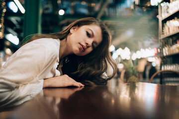 Portrait of beautiful Caucaisan model with brunette curly hair posing in shopping center spending daytime indoors, attractive female in stylish white shirt looking at camera in public place