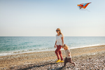 Family mother and child walking on beach with kite flying travel vacations healthy lifestyle mom...