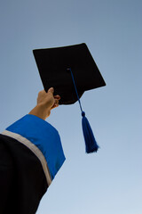 graduate in cap and gown, throwing a cap freely