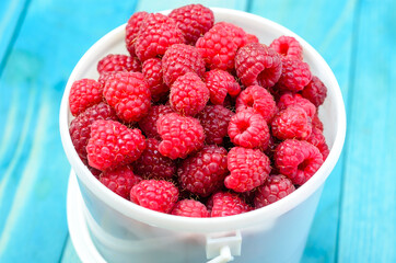 Raspberry bucket on white woodne boards