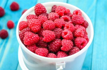 Raspberry bucket on white woodne boards