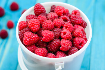 Raspberry bucket on colourful turquoise blue painted wooden boards