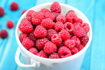 Raspberry bucket on white woodne boards