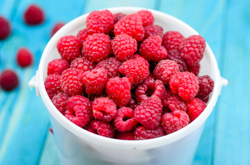 Raspberry bucket on colourful turquoise blue painted wooden boards