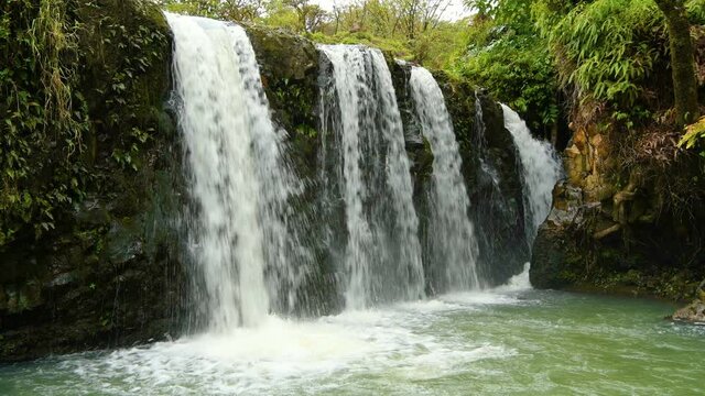 Waterfalls and Green Pond - Strong and broad waterfalls flowing into a clear green pond in Puaa Kaa State Wayside Park at side of the Road to Hana Highway, Maui, Hawaii, USA.