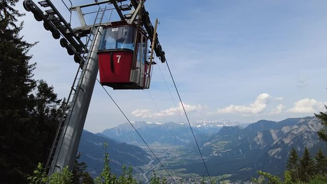 SLOW MOTION: Woman in Brambruesch in Switzerland. Swiss cable car of Chur or Coira with Swiss flag. Chur skyline in Grisons canton. Red cable car cabin from Chur to Kanzeli and Brambruesch.
