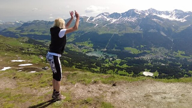 SLOW MOTION: Girl jumping on Piz Scalottas top. Tourist resort in Plessur Alps of Switzerland in Grisons.