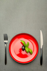 Diet. Small amount of food on the plate. One olive is in a red plate, a knife and a fork. Weight...