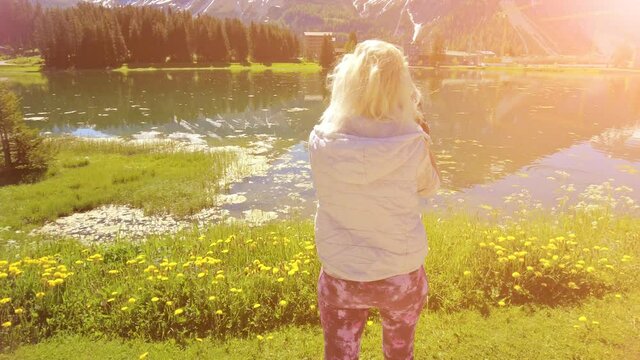 Woman photographer at sunset taking pictures at Arosa town, tourist resort by Obersee Lake in Switzerland. Arosa lakefront by cable car station to Aroser Weisshorn peak. Plessur Region in Graubunden.