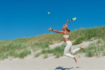 Young girl playing beach tennis on sand. Professional sport concept