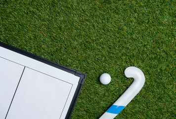 Field hockey stick,  ball and coach table on the green field. Professional sport concept