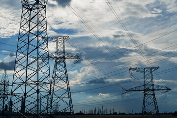 High-voltage electric lines, towers and industrial infrastructure against the blue sky