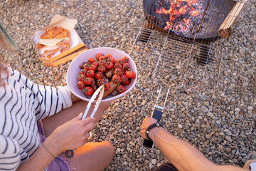 Grilling tomatoes and sausages outdoors, close-up