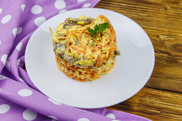 Tasty salad with pork heart, carrot in Korean, onion,  cheese and mayonnaise on wooden table