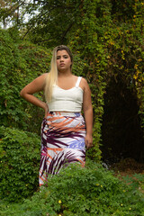 Young blonde leaning in a garden in the late afternoon