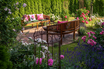 Rundbank mit Kissen auf einem Steinkreis in einem wunderschönen farbenfrohen Garten mit vielen Rosen