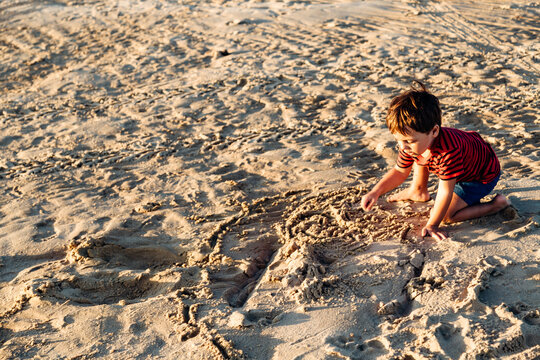 Little boy playing with the sand of the beach in a sunset of someday of summer. Santa Ana, Entre Rios, Argentina.