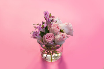 a beautiful bouquet of flowers in a transparent vase with water on a pink background.  pink flowers. the concept of love, romance