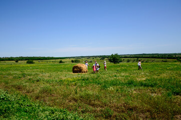 A group of people spend a weekend in nature, taking pictures in a haystack.