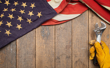 American flag drapped over an old workbench with a hand holding a wrench