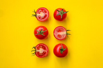 Red tomatoes, whole and sliced, isolated on a yellow background. Beautiful picture. Top view. 