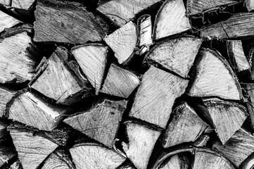 textured firewood background of chopped wood for kindling and heating the house. a woodpile with stacked firewood. the texture of the birch tree. toned in black white or gray color