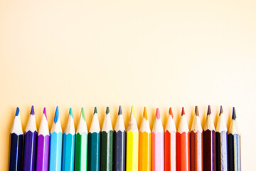 Row of colour pencils isolated on orange background