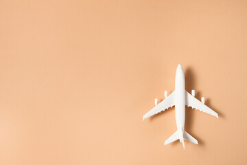 Flat lay design of travel concept with plane on brown background.