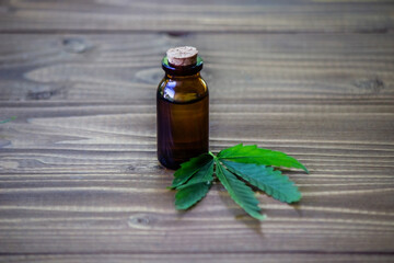 cannabis leaves on wood background with bottles, cannabis oil.