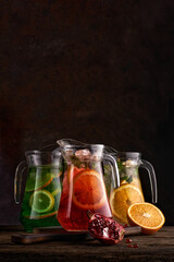 Set of colorful lemonades in jugs. On dark background